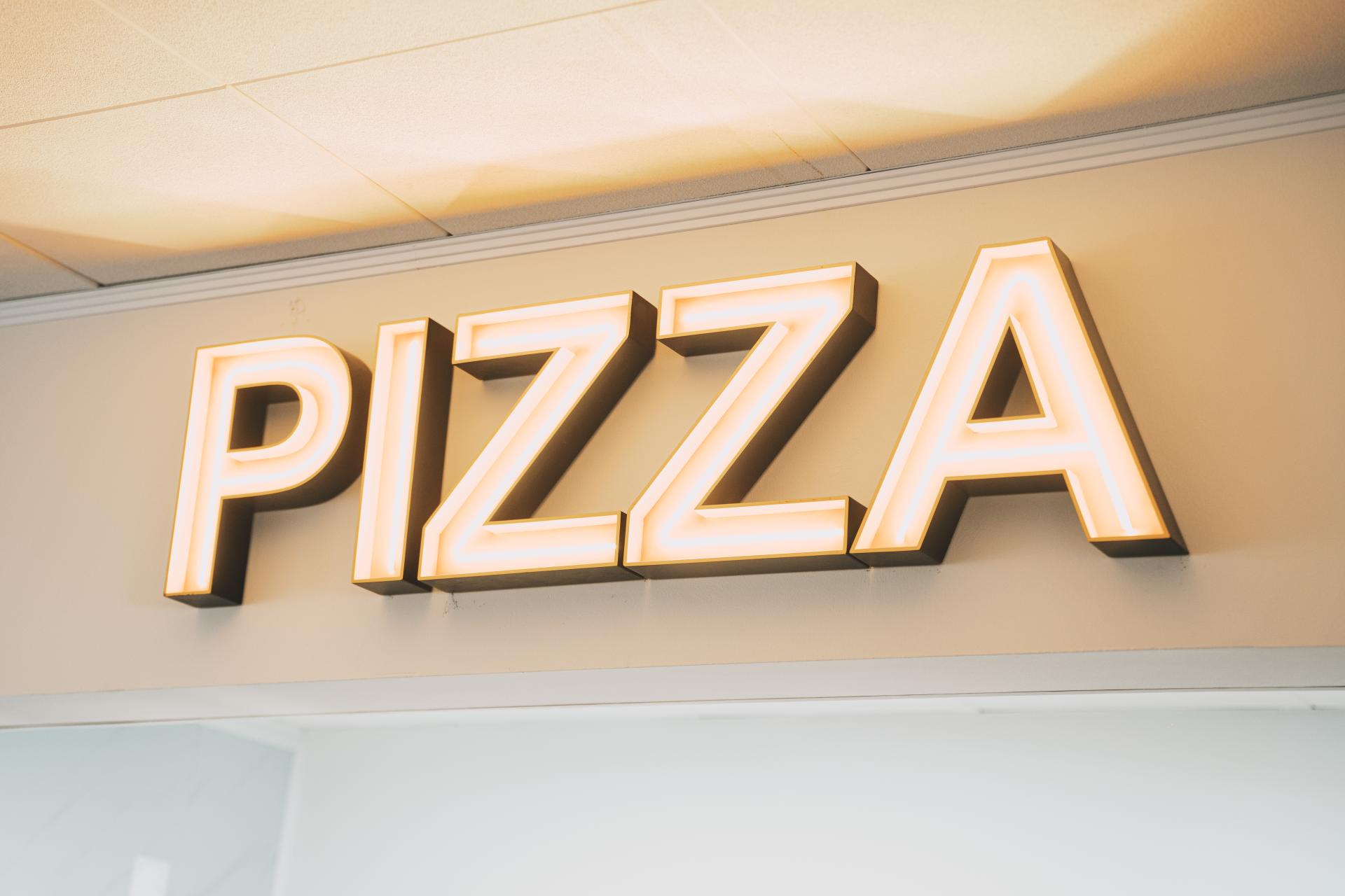 Letreiro luminoso PIZZA na sala do restaurante